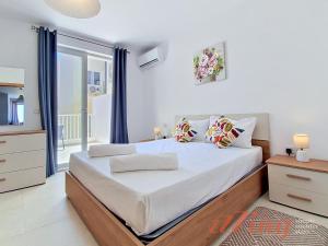 a bedroom with a large bed and a large window at Merhba Court Apartments - St Pauls Bay in St. Paul's Bay