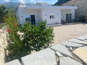 a white house with some plants in front of it at Klea Rooms in Himare