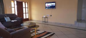 a living room with a table and a tv on the wall at Abodes at 113 in Manzini