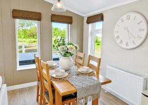 a dining room with a table and a clock on the wall at Bosworth Lakeside Lodges in Carlton