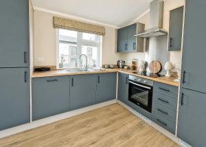a kitchen with blue cabinets and a sink at Bosworth Lakeside Lodges in Carlton +45 photos