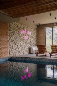 a swimming pool with two chairs next to a rock wall at Gudauri Inn in Gudauri