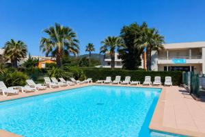 a swimming pool with chairs and palm trees at Carre Marine N12 - 2P4 in Mandelieu-La Napoule