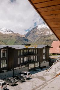 a building with cars parked in a parking lot with mountains at Gudauri Inn in Gudauri