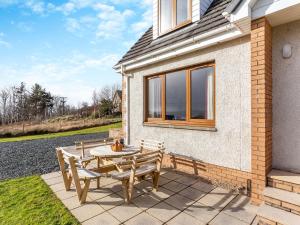 a patio with a table and chairs in front of a house at Bramble Cottage in Gairloch