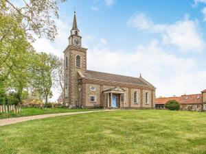 a church with a tower with a clock on it at Barwick Lodge in Bawdeswell