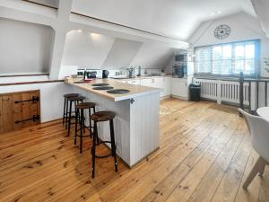 a large kitchen with a counter and stools in it at The Flat The Farm in Godstone
