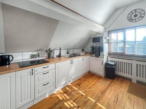 a kitchen with white cabinets and a clock on the wall at The Flat The Farm in Godstone