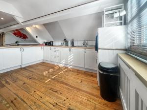 a kitchen with white cabinets and a wooden floor at The Flat The Farm in Godstone +8 photos