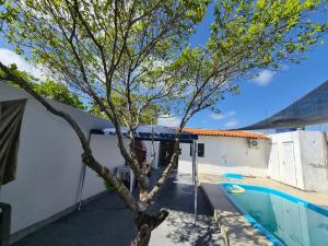 a tree in the courtyard of a house with a swimming pool at Descanso das Águas in Santo Amaro
