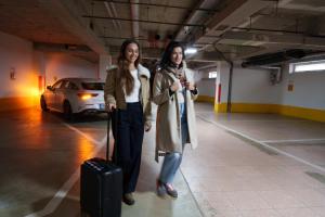 two women walking in a parking lot with a suitcase at Apartments Kopecna with garage parking possible in Brno