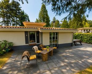 a patio with a table and chairs in front of a house at Villa Mar veluwe in Ermelo