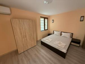 a bedroom with a bed and a wooden cabinet at Червената къща in Hisarya