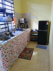 a kitchen with a counter with a sink and a refrigerator at Rumah Kuning Homestay in Bachok