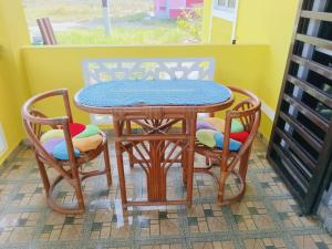 a wooden table and two chairs with a table and a table at Rumah Kuning Homestay in Bachok