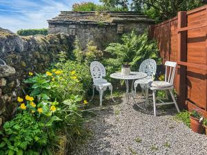 a table and chairs in a garden with flowers at Emily's Cottage in Hebden