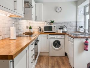 a kitchen with white cabinets and a washer and dryer at Emily's Cottage in Hebden