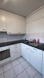 a kitchen with white cabinets and a sink at Charmantes Studio in Solothurn