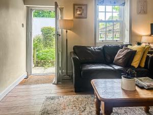 a living room with a black leather couch and a table at Emily's Cottage in Hebden