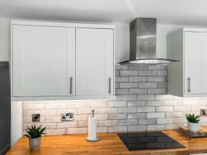 a kitchen with white cabinets and a wooden counter top at Emily's Cottage in Hebden +19 photos
