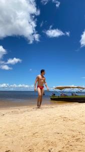 a woman standing on a beach next to a boat at Caju Hostel in Alter do Chao