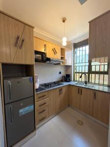 a kitchen with wooden cabinets and a stainless steel refrigerator at Elite Apartments Masaka in Kigali