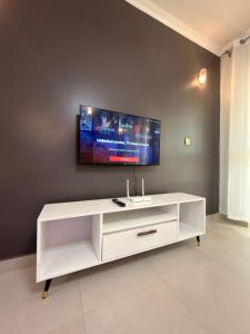 a white entertainment center with a tv on a wall at Elite Apartments Masaka in Kigali