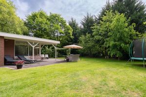 a backyard with a patio and an umbrella at De Vlinderstruik | 4 persons in Gasselte