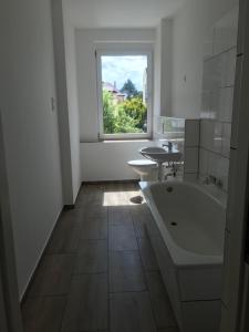 a bathroom with a tub and a sink and a window at Arnold Apartments in Glauchau