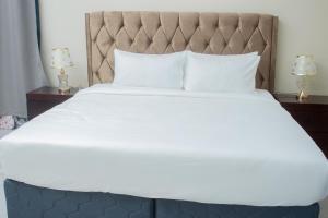 a large bed with white sheets and two lamps at Monga's Apartments in Ndola