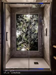 a shower with a glass door with a plant mural at Suites avec Jacuzzi Privé & Terrasse - Vieille Ville d'Annecy in Annecy