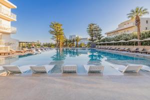 a swimming pool with chairs and umbrellas at a hotel at Marilena Hotel in Amoudara Herakliou