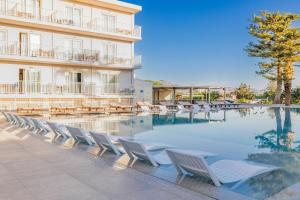 a row of lounge chairs next to a hotel swimming pool at Marilena Hotel in Amoudara Herakliou
