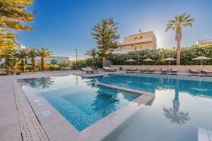 a swimming pool with chairs and trees and a building at Marilena Hotel in Amoudara Herakliou +35 photos