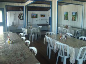 un comedor con mesas blancas y sillas blancas en Dona Quinota, en Ilha do Mel
