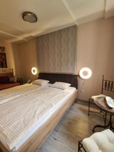 a bedroom with a large bed and two lamps at Götzer Apartman in Komló