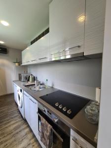 a kitchen with white cabinets and a black counter top at Götzer Apartman in Komló