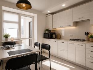 a kitchen with white cabinets and a table and chairs at Апартаменти 2-кім Тарнавського in Ternopil