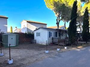 a small white house with trees and a fence at El Moll Grec in L'Escala