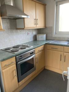 a kitchen with wooden cabinets and a stove top oven at Great for commuting, budget friendly apartment in Dalmuir