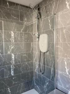 a shower in a bathroom with a black marble wall at Great for commuting, budget friendly apartment in Dalmuir