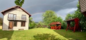 a rainbow in the sky behind a house and a playground at На Пагорбі in Mykulychyn