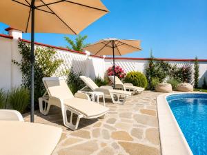 a patio with chairs and umbrellas next to a pool at Villa Topola Bay View in Topola