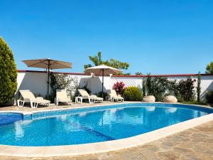 a large swimming pool with chairs and umbrellas at Villa Topola Bay View in Topola