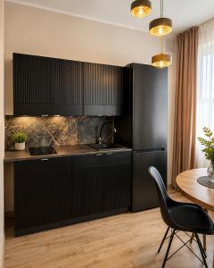 a kitchen with a black refrigerator and a table at Apartament Contra II in Wodzisław Śląski