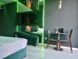 ein grünes Schlafzimmer mit Bett, Tisch und Stühlen in der Unterkunft Motel Século in Lousada