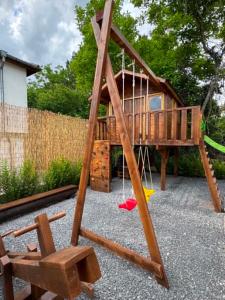 a playground with a tree house and a swing at Helena Guest House - Pool & Sea View in Balchik