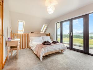 a bedroom with a bed and a desk and windows at The Larches - Uk46804 in Culbokie +15 photos