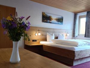 a bedroom with a bed and a vase of flowers on a table at Pension Edelweiss in Damuls