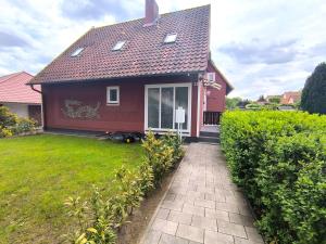 a small red house with a walkway in the yard at Ferienwohnung-Heide-3 in Walsrode